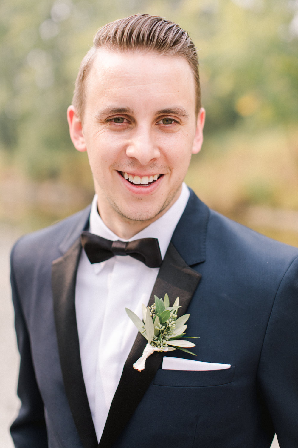 portrait of groom smiling at fish creek park in Calgary at the lake house in Calgary