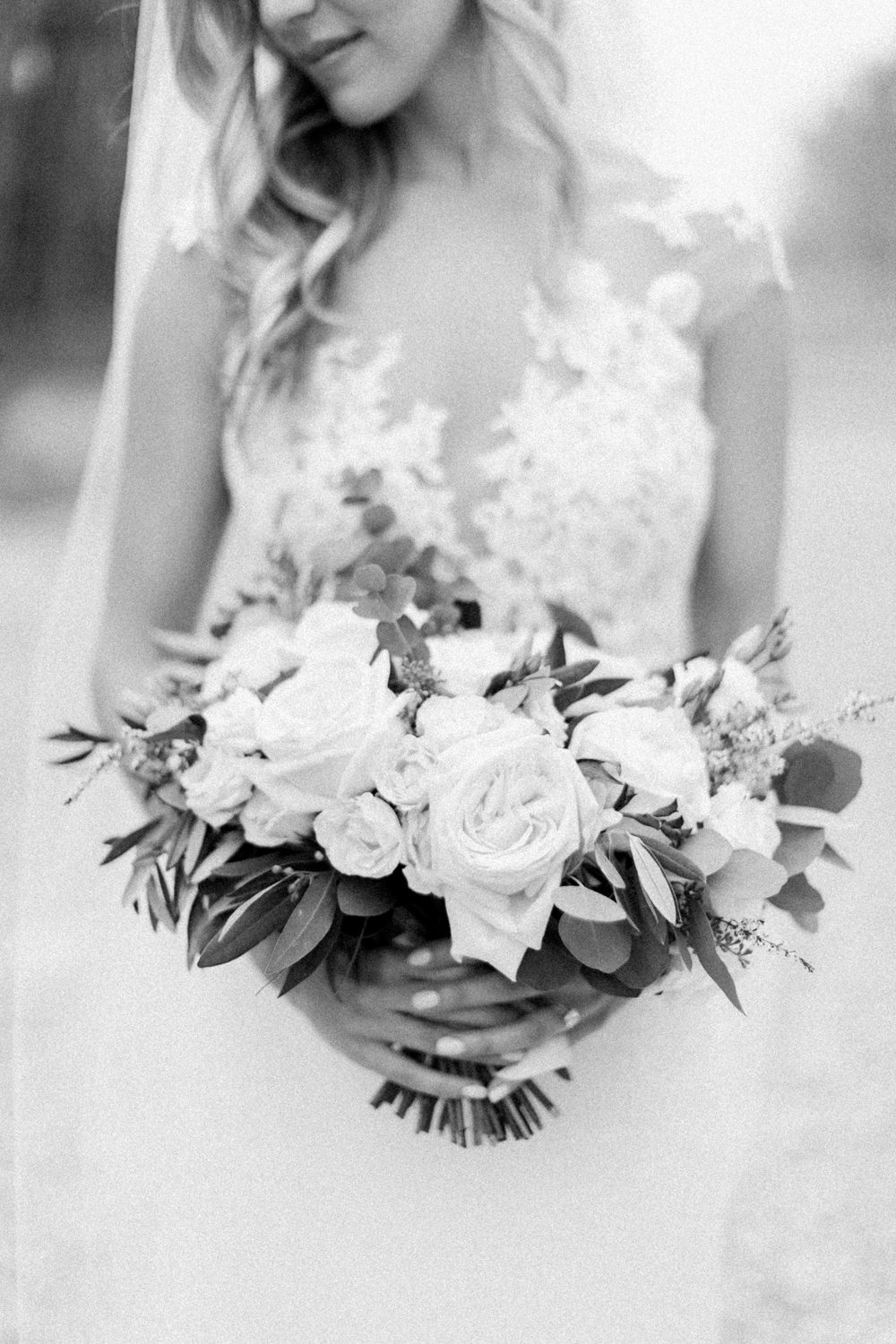 black and white detail shot of  bride holding wedding bouquet at fish creek park in Calgary at the lake house in Calgary