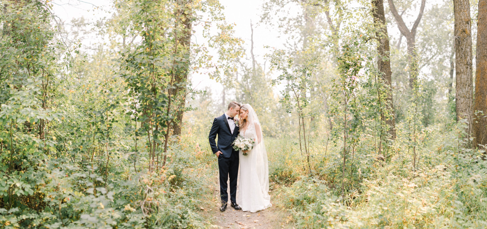  a panoramic full body portrait of the bride and groom fish creek park in Calgary at the lake house in Calgary