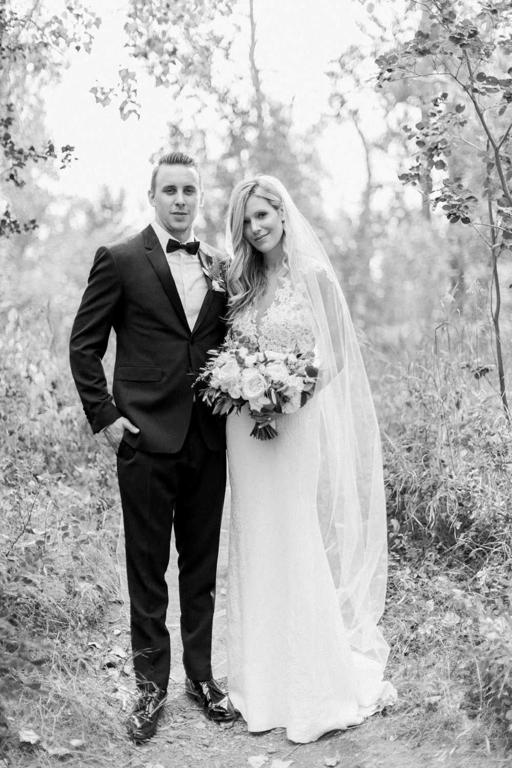 a black and white full body portrait of the bride and groom fish creek park in Calgary at the lake house in Calgary