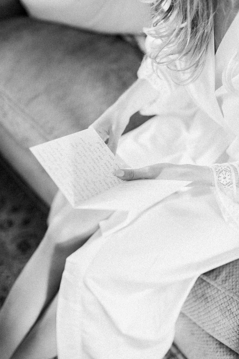 close up detail of bride in robe opening letter at the lake house in Calgary