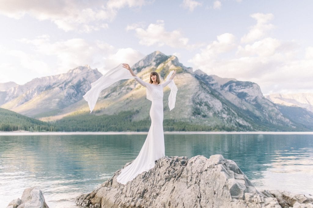 Bride posing onto of rocks at Lake Minnewanka in Banff National Park