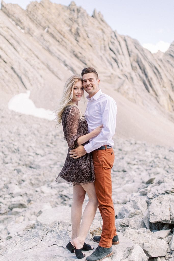 Banff national park summer engagement session of couple standing on mountain ridge holding each other