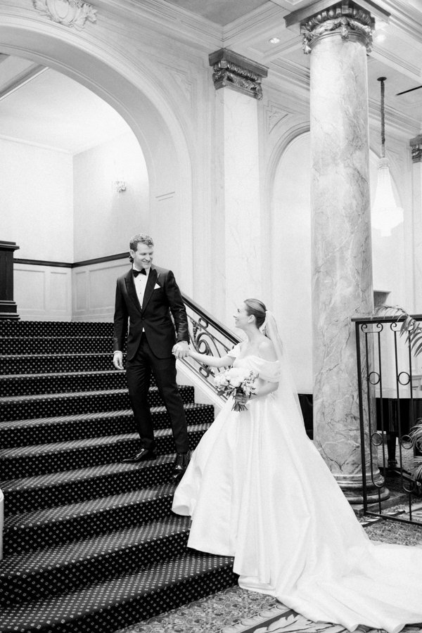 wide shot of bride and groom walking up the stairs on the grand stair case at the Calgary Fairmont Palliser Hotel