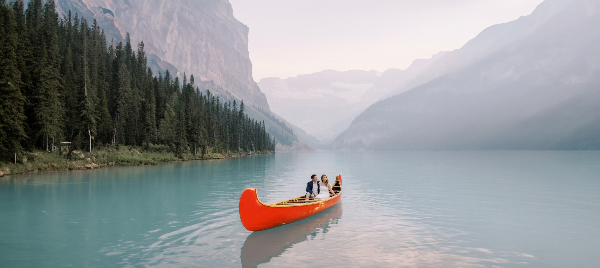 Couple in red canoe on Lake Louise during sunset