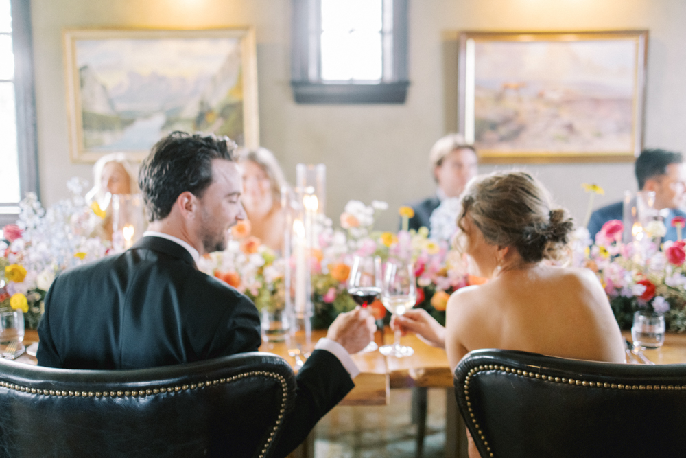 a couple sitting at the table during their wedding reception.