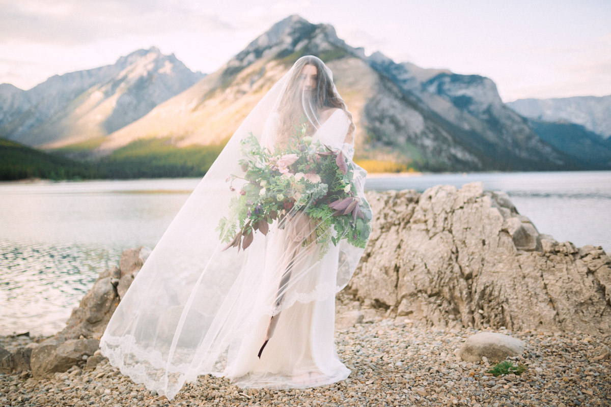 bide with veil and big floral arrangement on the shore of lake Minnewanka in Banff